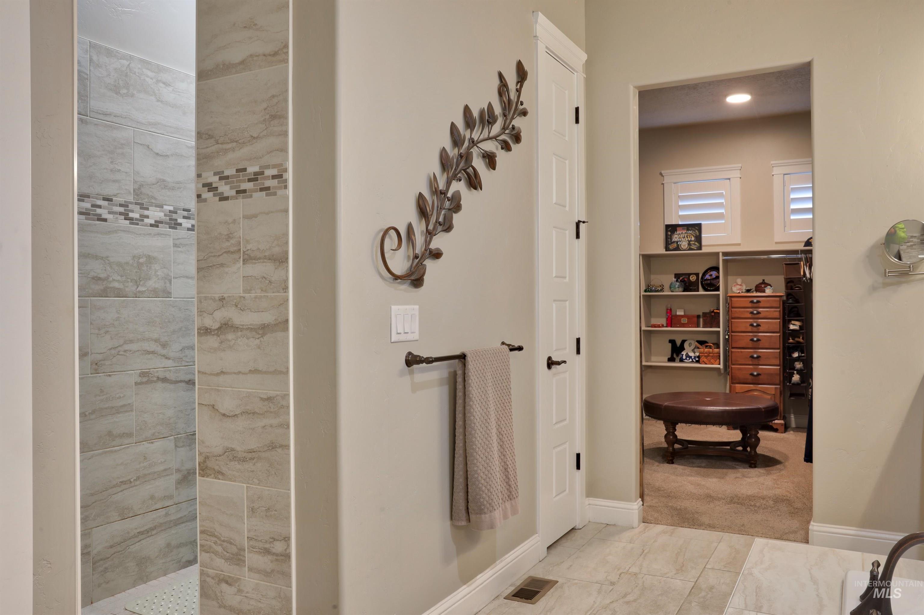 Bathroom with tiled shower and baseboards