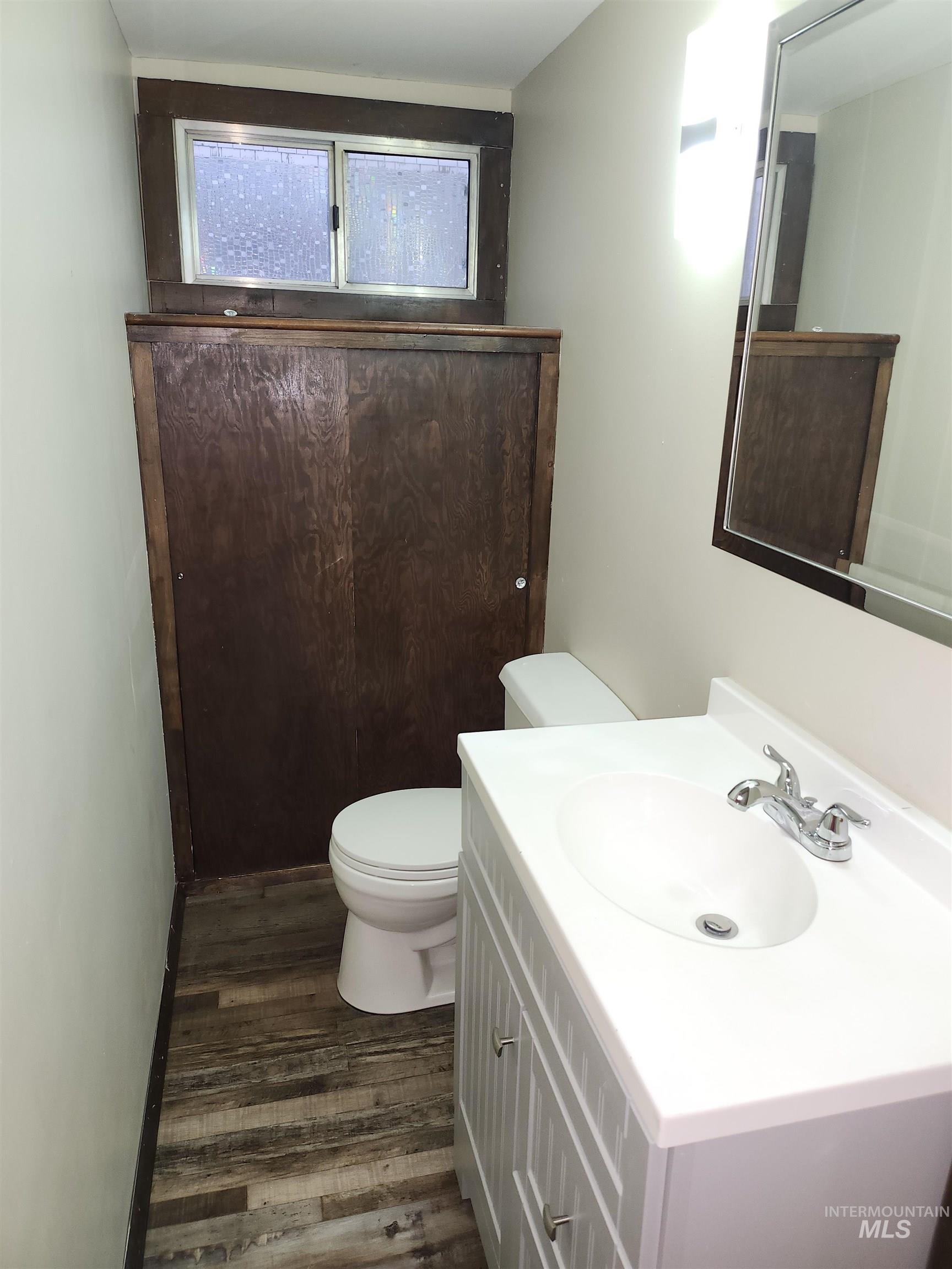 Half bath featuring dark wood-style floors and vanity