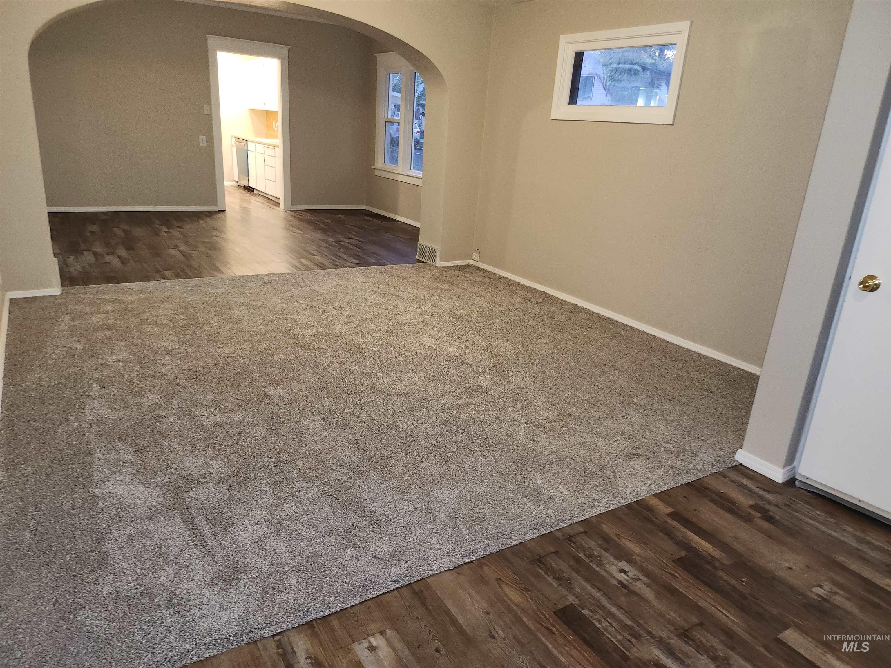 Unfurnished room featuring arched walkways and dark wood-type flooring