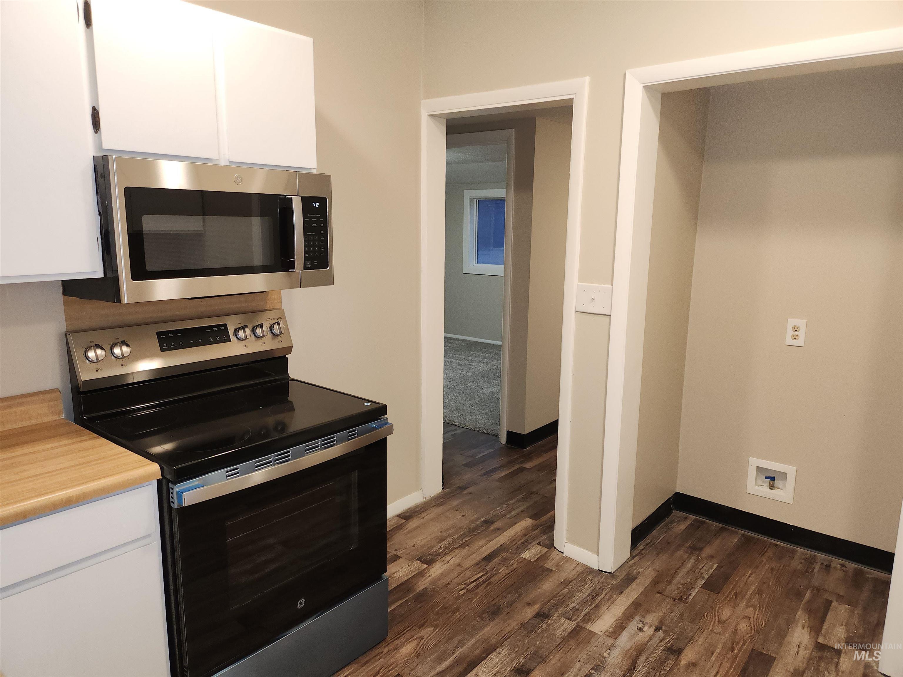 Kitchen with appliances with stainless steel finishes, light countertops, and white cabinetry