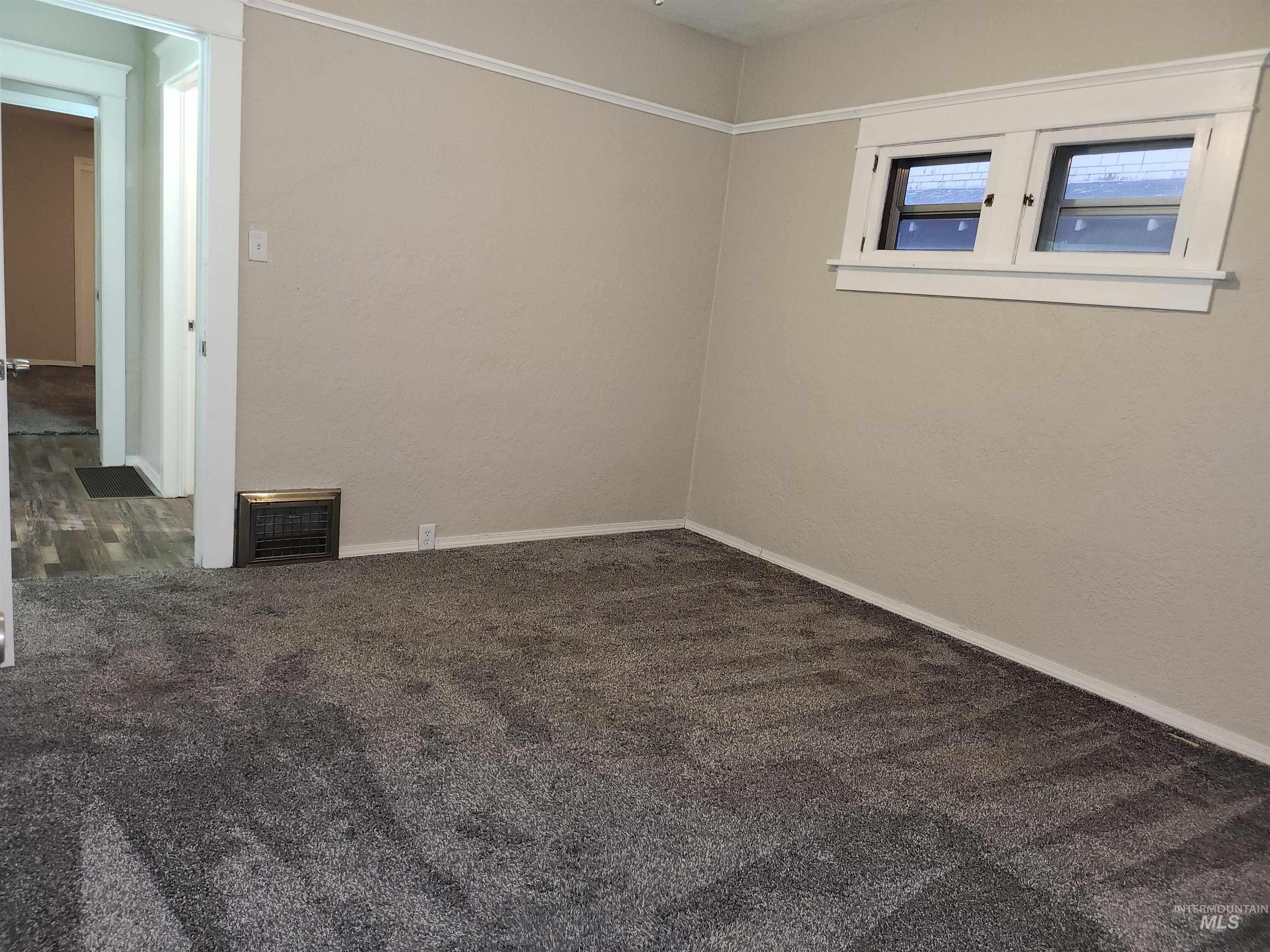 Spare room with dark carpet and baseboards