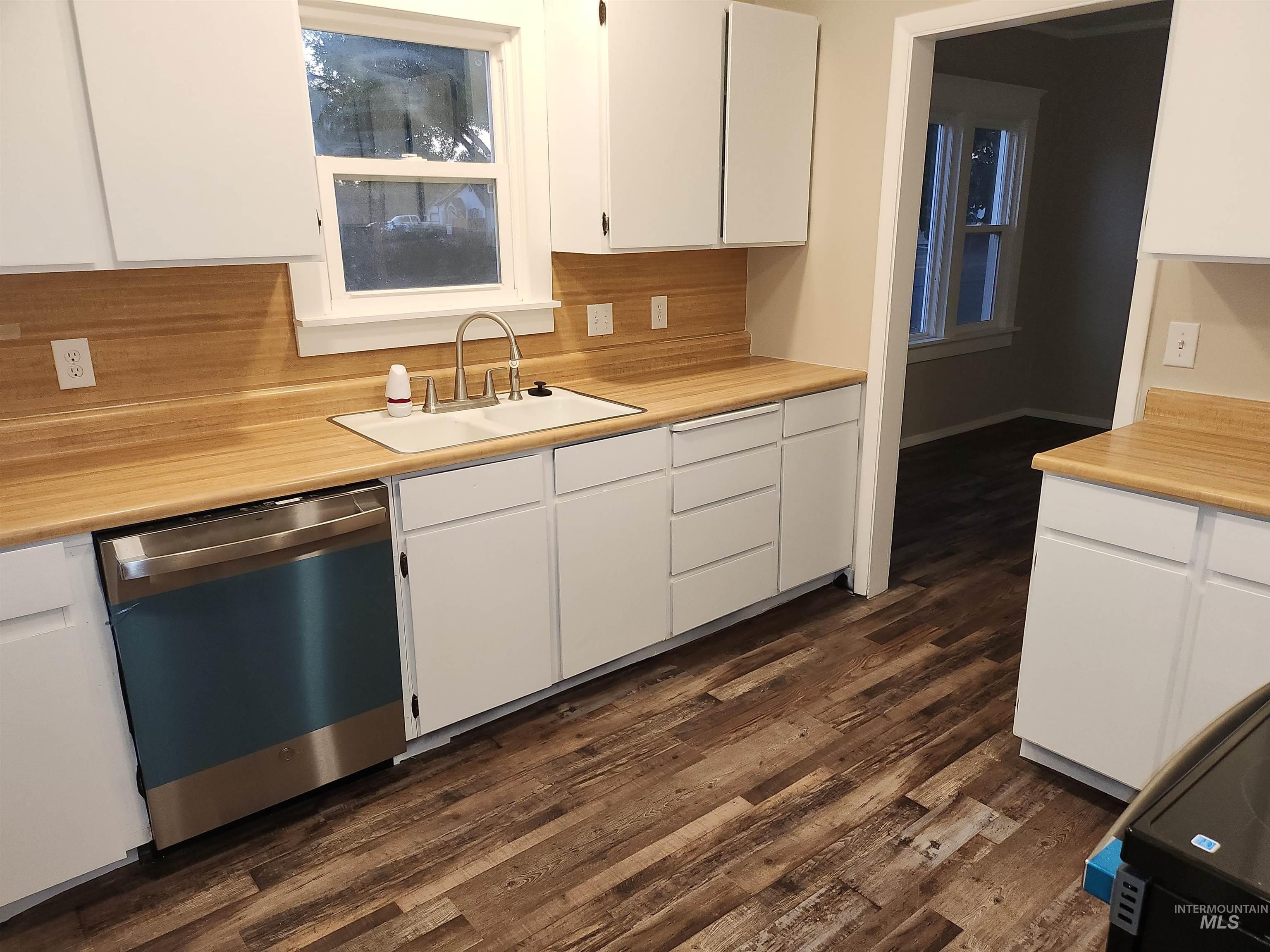 Kitchen featuring white cabinetry, light countertops, and stainless steel dishwasher