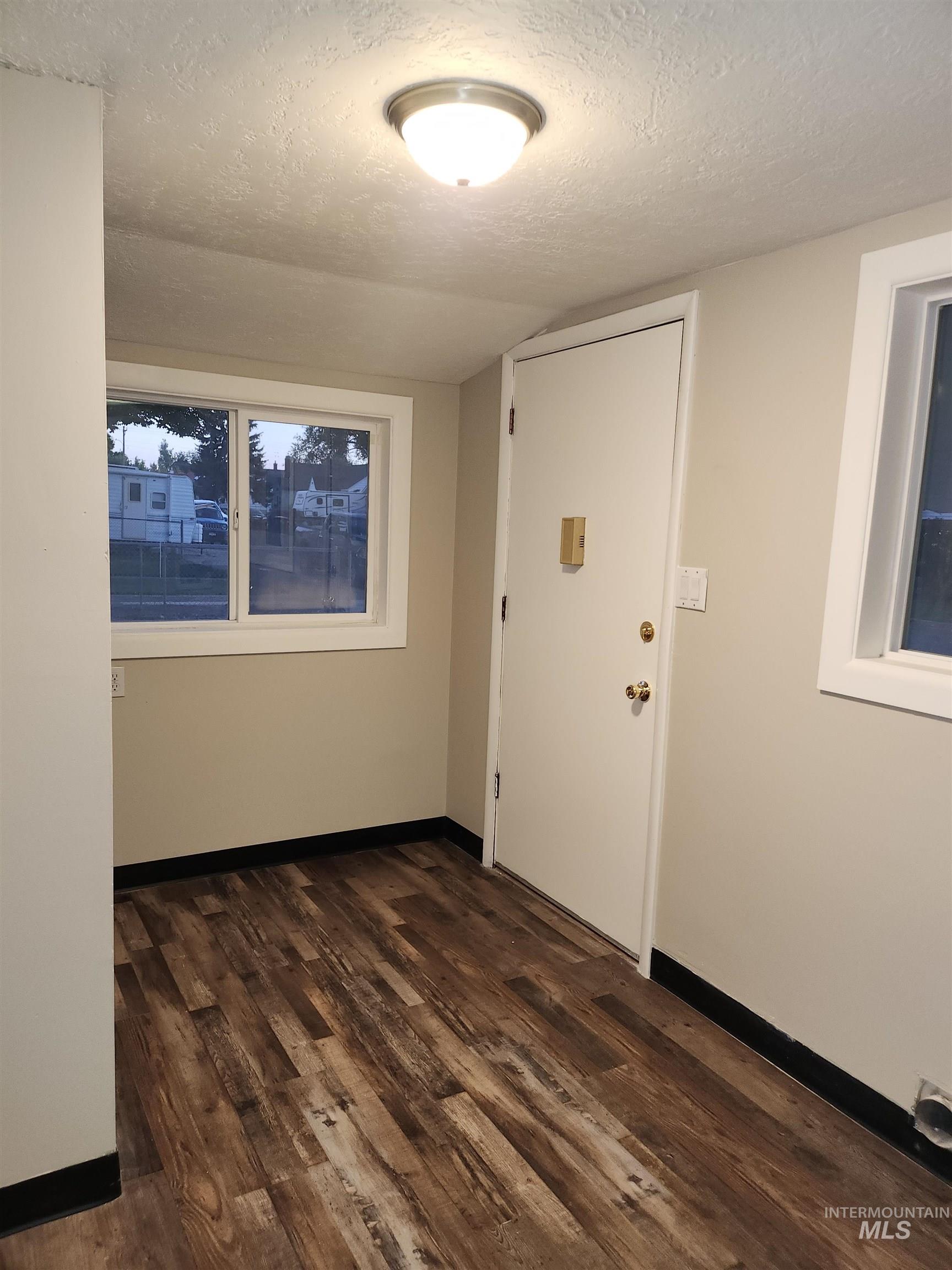Entrance foyer featuring a textured ceiling and dark wood-style flooring