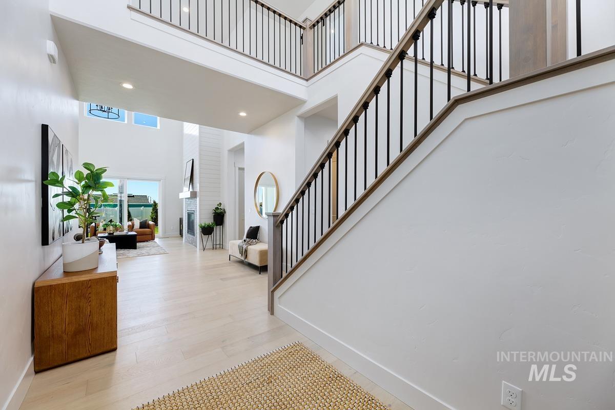 Entryway featuring a towering ceiling, stairway, recessed lighting, and light wood-style flooring