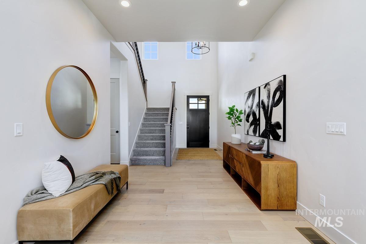 Entryway featuring light wood-style floors, stairway, recessed lighting, and a high ceiling