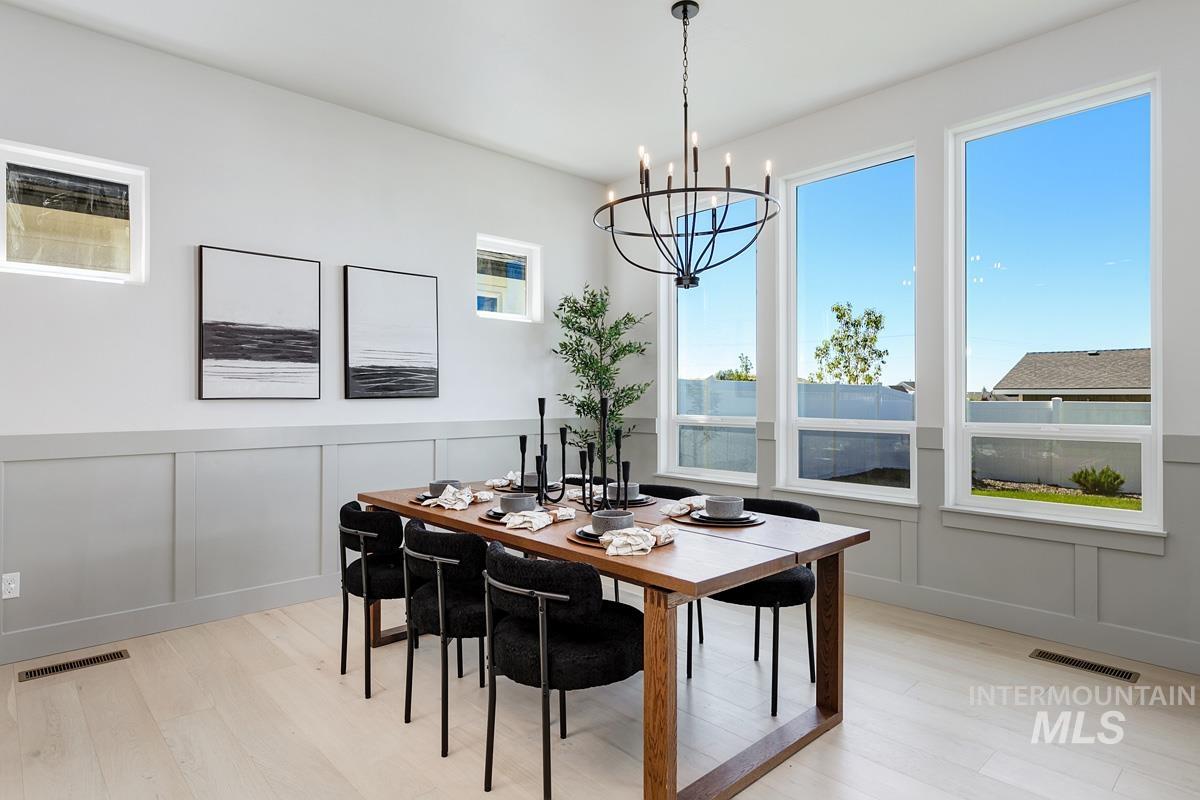 Dining area featuring a decorative wall, light wood finished floors, and a chandelier