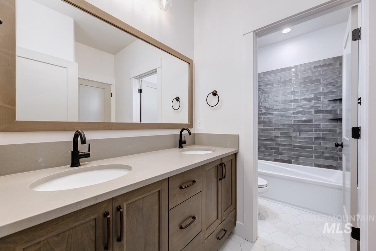 Full bathroom with double vanity, light tile patterned flooring, and bathtub / shower combination