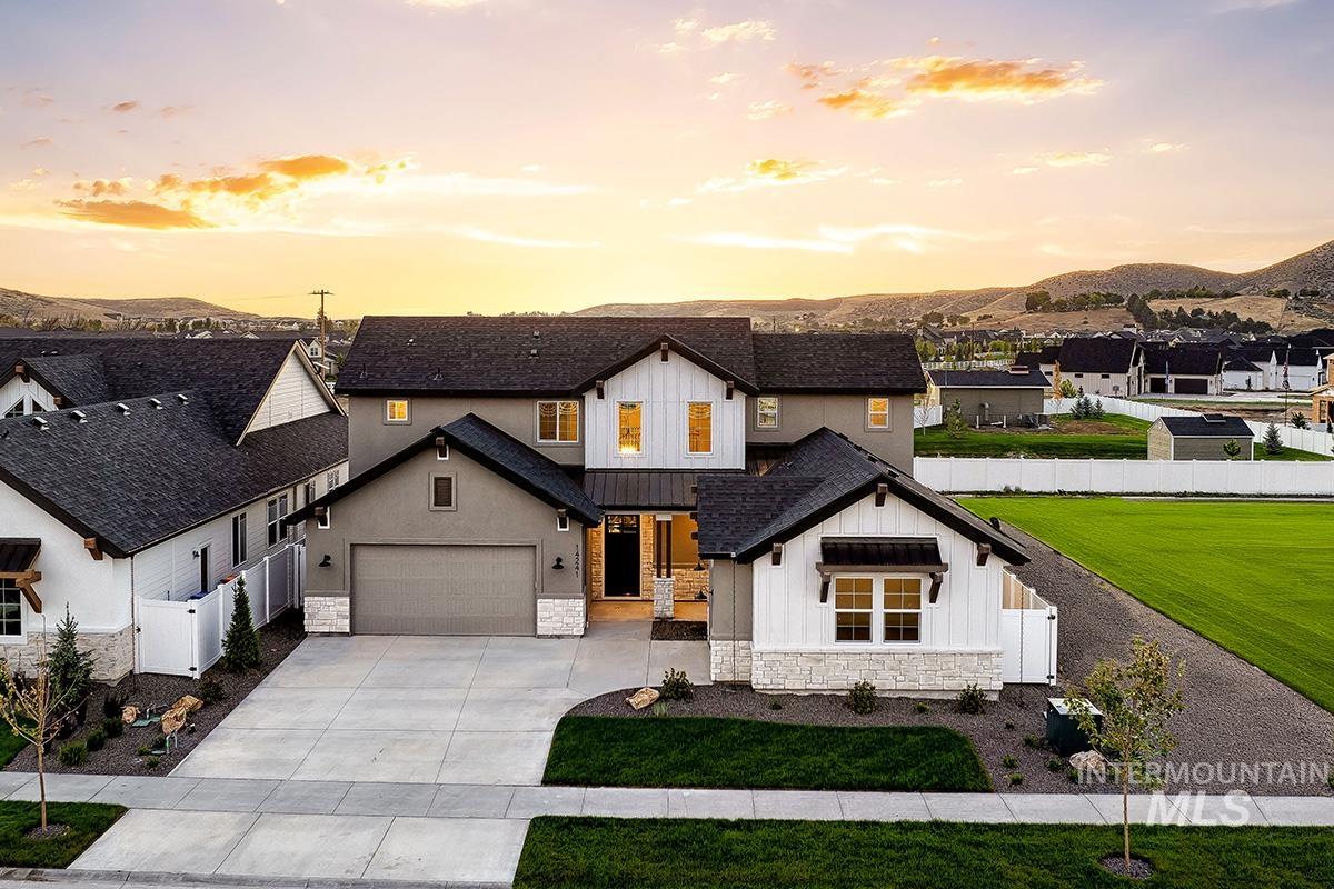 Modern inspired farmhouse with board and batten siding, stone siding, concrete driveway, roof with shingles, and a mountain view