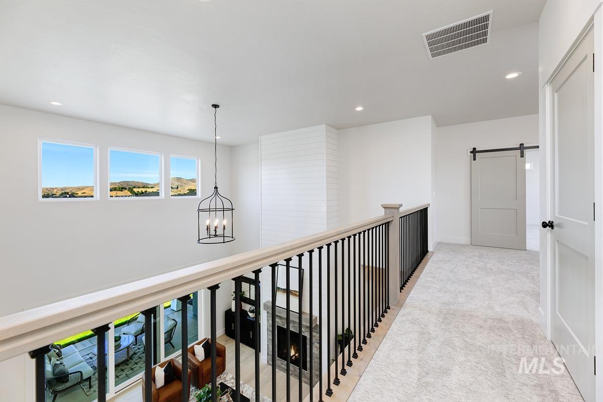 Hallway with a barn door, light carpet, a chandelier, and recessed lighting