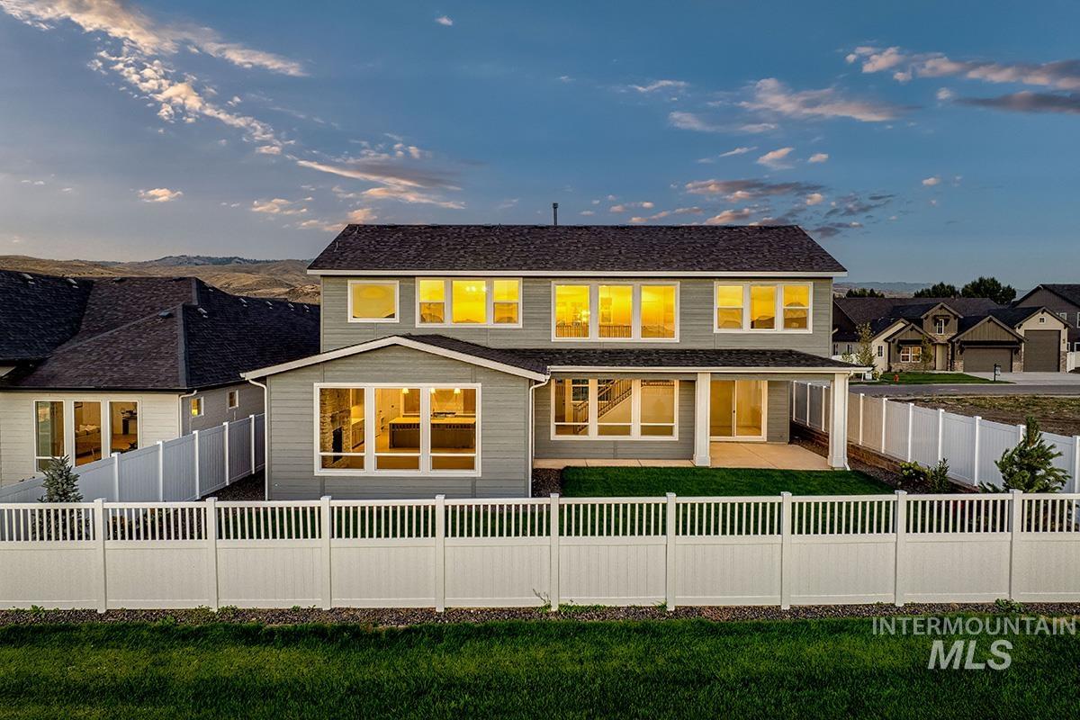Back of house at dusk with a patio and a fenced backyard