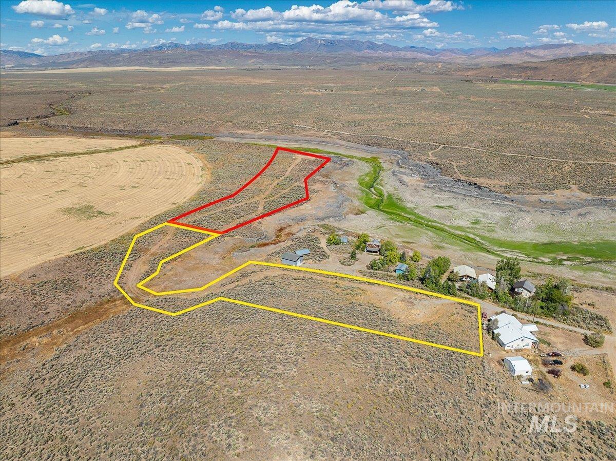 Aerial view of sparsely populated area featuring property parcel outlined and a mountain backdrop