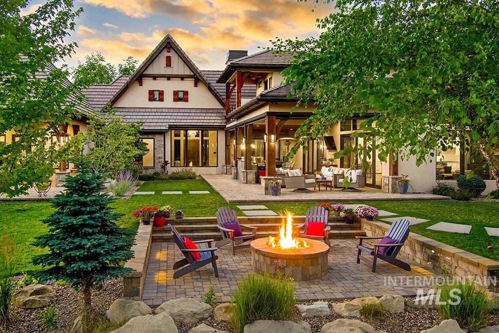 Back of house at dusk with an outdoor living space with a fire pit, a patio area, a lawn, a tile roof, and stucco siding
