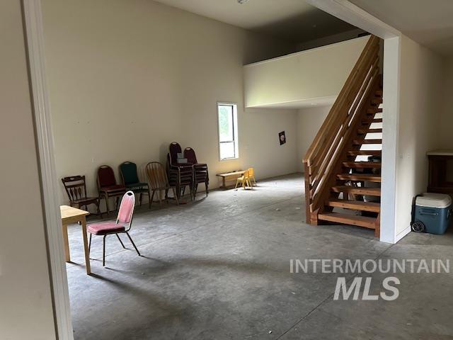 Sitting room featuring concrete flooring and stairway
