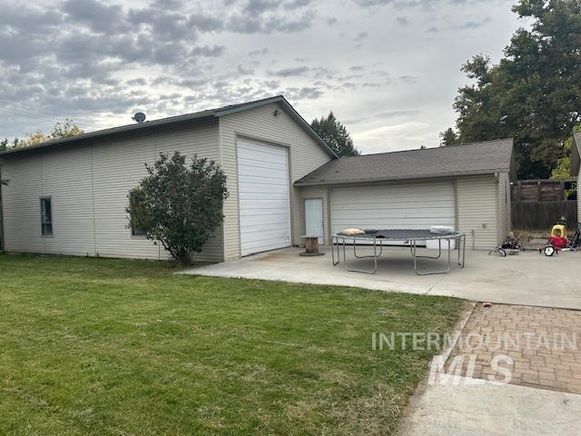 Rear view of property featuring a patio area, a yard, and a trampoline