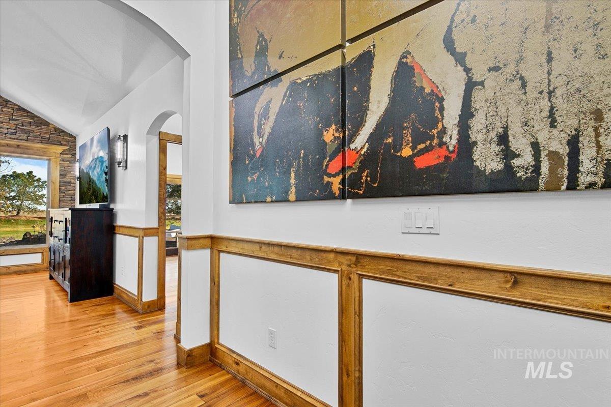 Hardwood flooring with natural wood wainscoting and arched doorways
