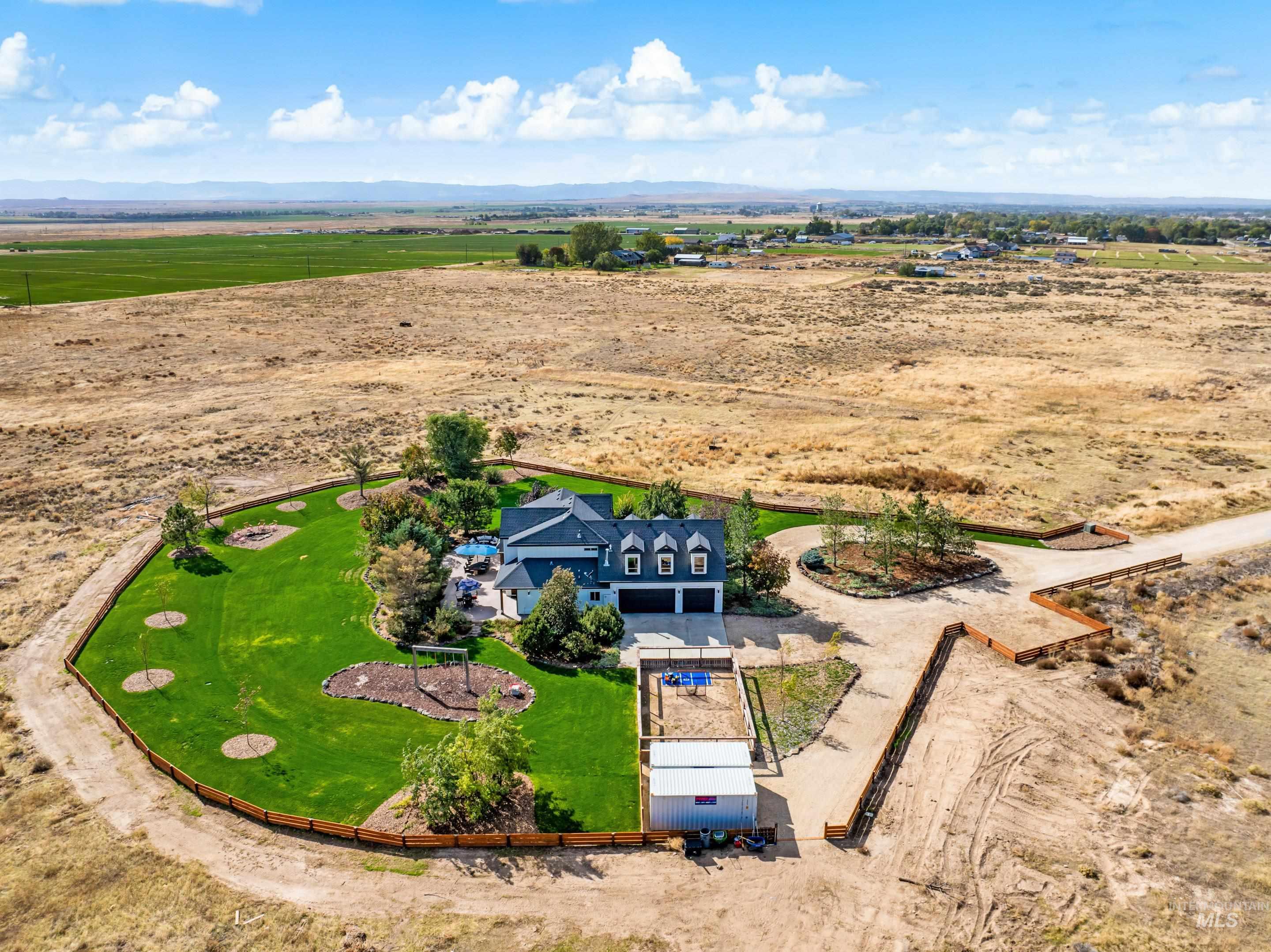 Expansive property featuring a meticulously manicured lawn, a gravel driveway, and a separate outbuilding