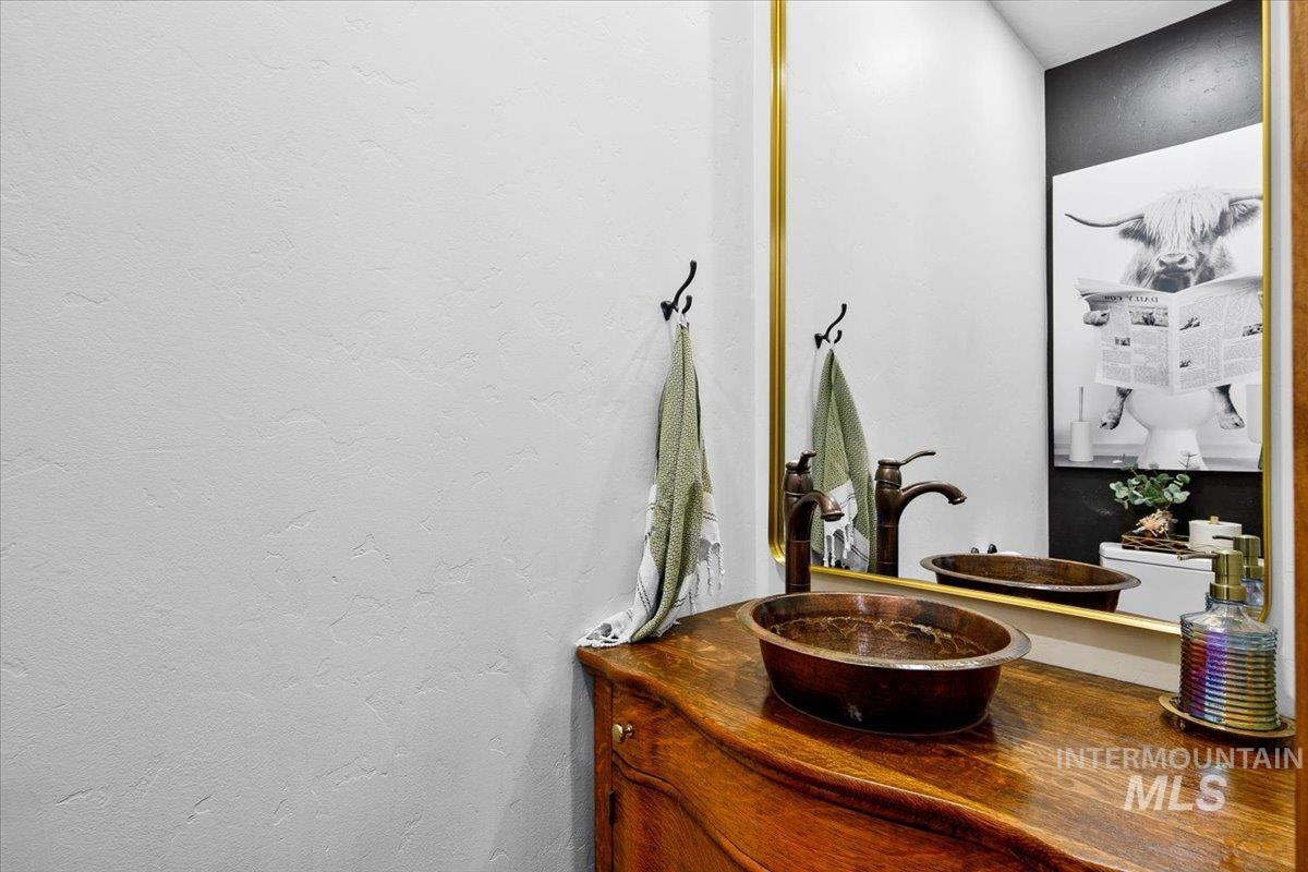 Vanity featuring a copper vessel sink and oil-rubbed bronze faucet set on a wood-finish countertop