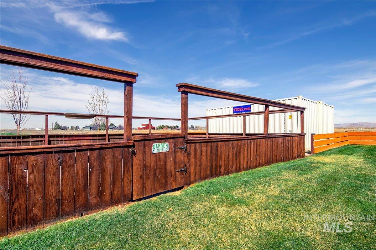 Stained wood perimeter fence with gate opening onto a grassy area