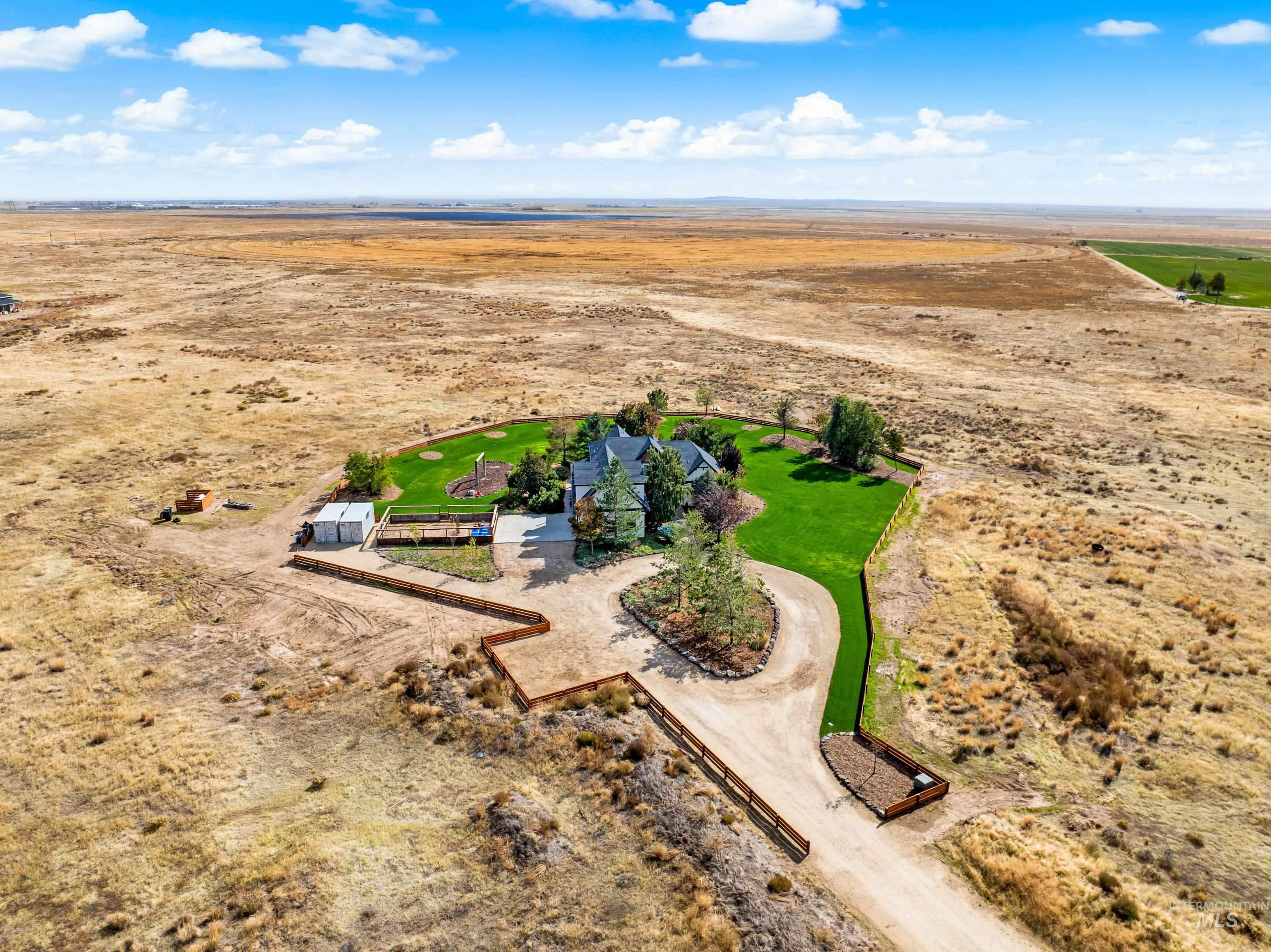 Single-family home featuring a manicured lawn, expansive paved driveway, and multiple outbuildings