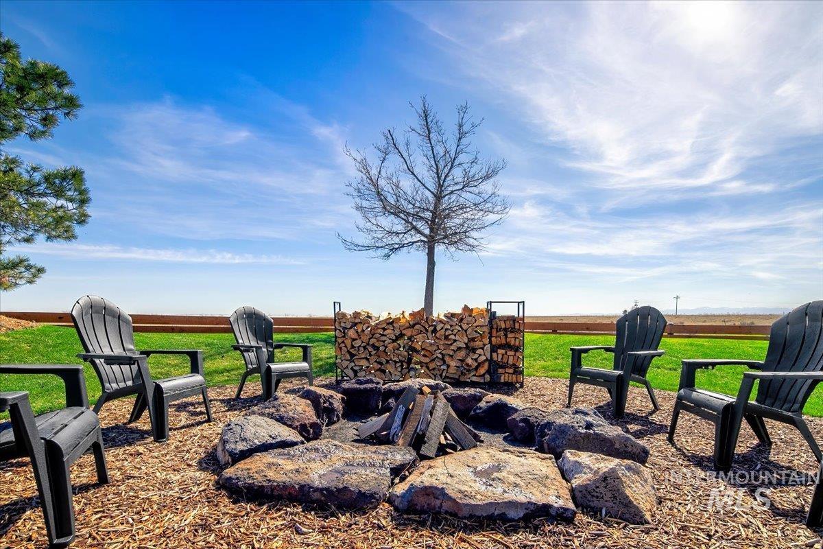 Outdoor fire pit area with stone surround, wood chip ground cover, and stacked firewood storage