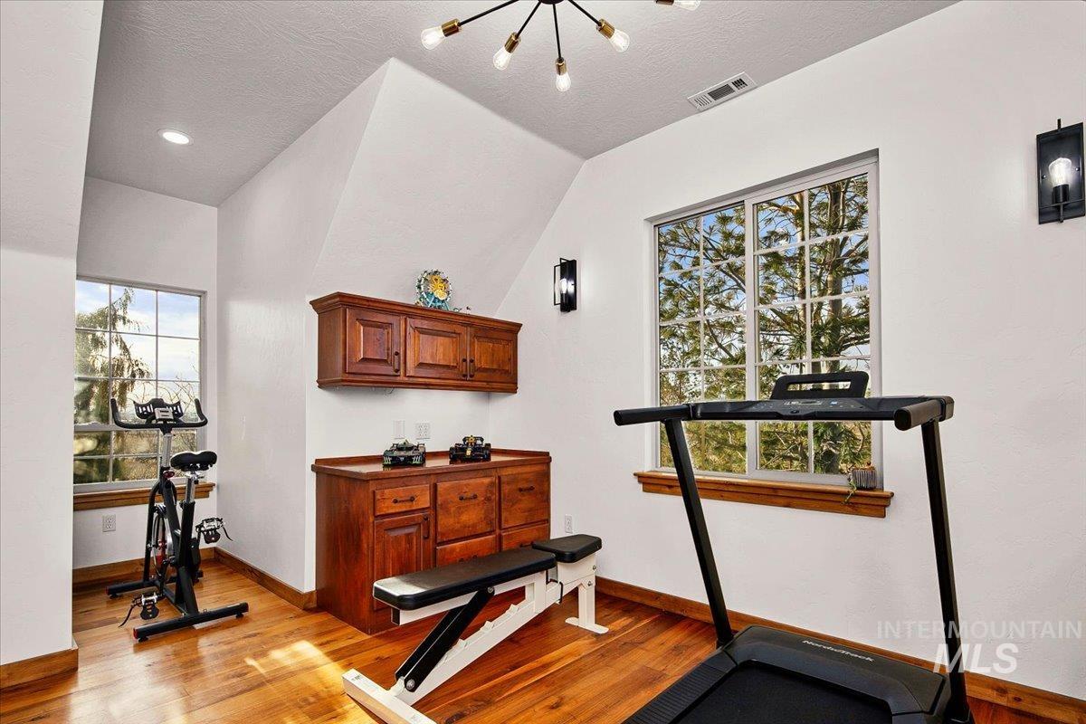 Room with wood-finish flooring, two large multi-pane windows, and a built-in wood-finish cabinet with a countertop