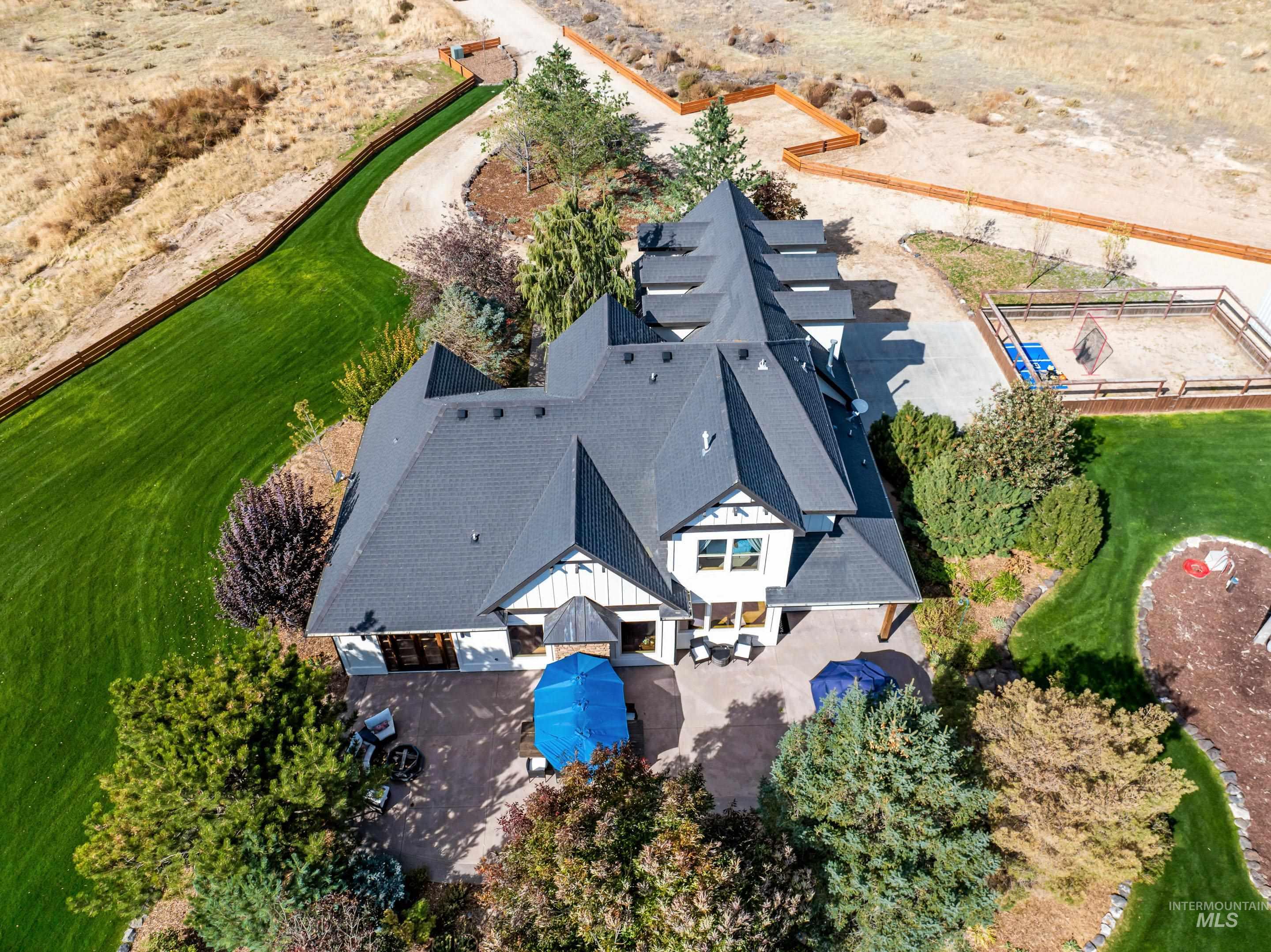 Aerial perspective showcasing a modern farmhouse-style residence with a dark shingle roof and white siding accents