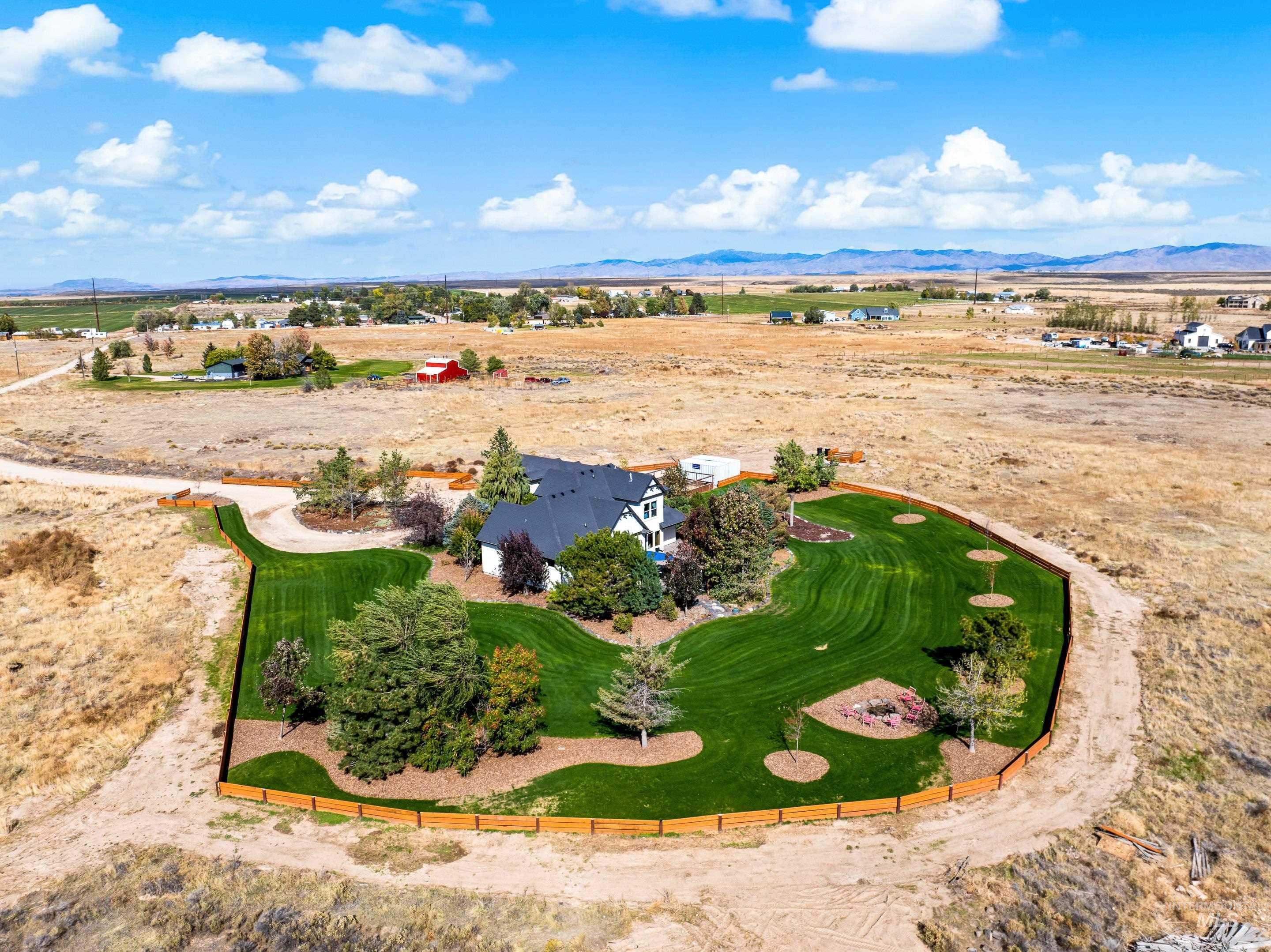 Expansive property featuring a manicured lawn, established landscaping, and a perimeter fence