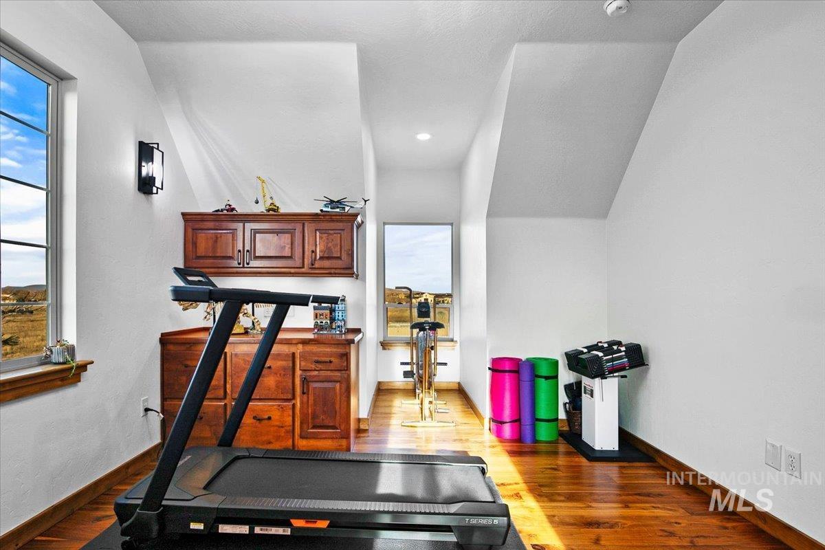 Attic space featuring wood-finish flooring, white walls, and built-in wood cabinetry