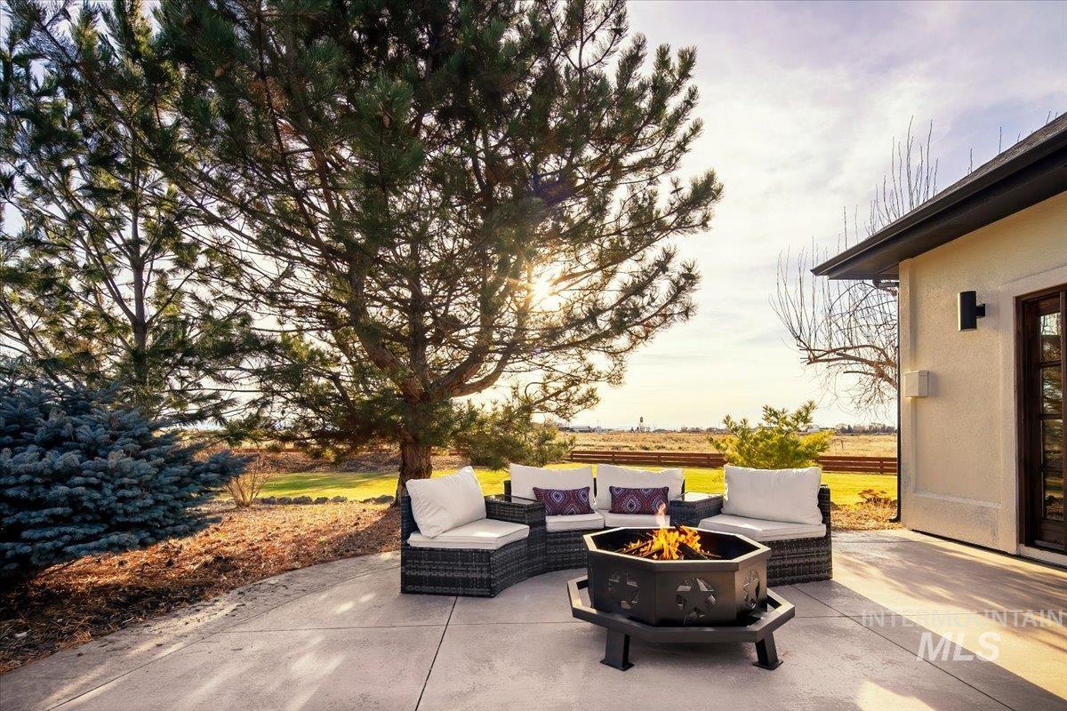 Concrete patio with a fire pit, bordered by mature trees and landscaping