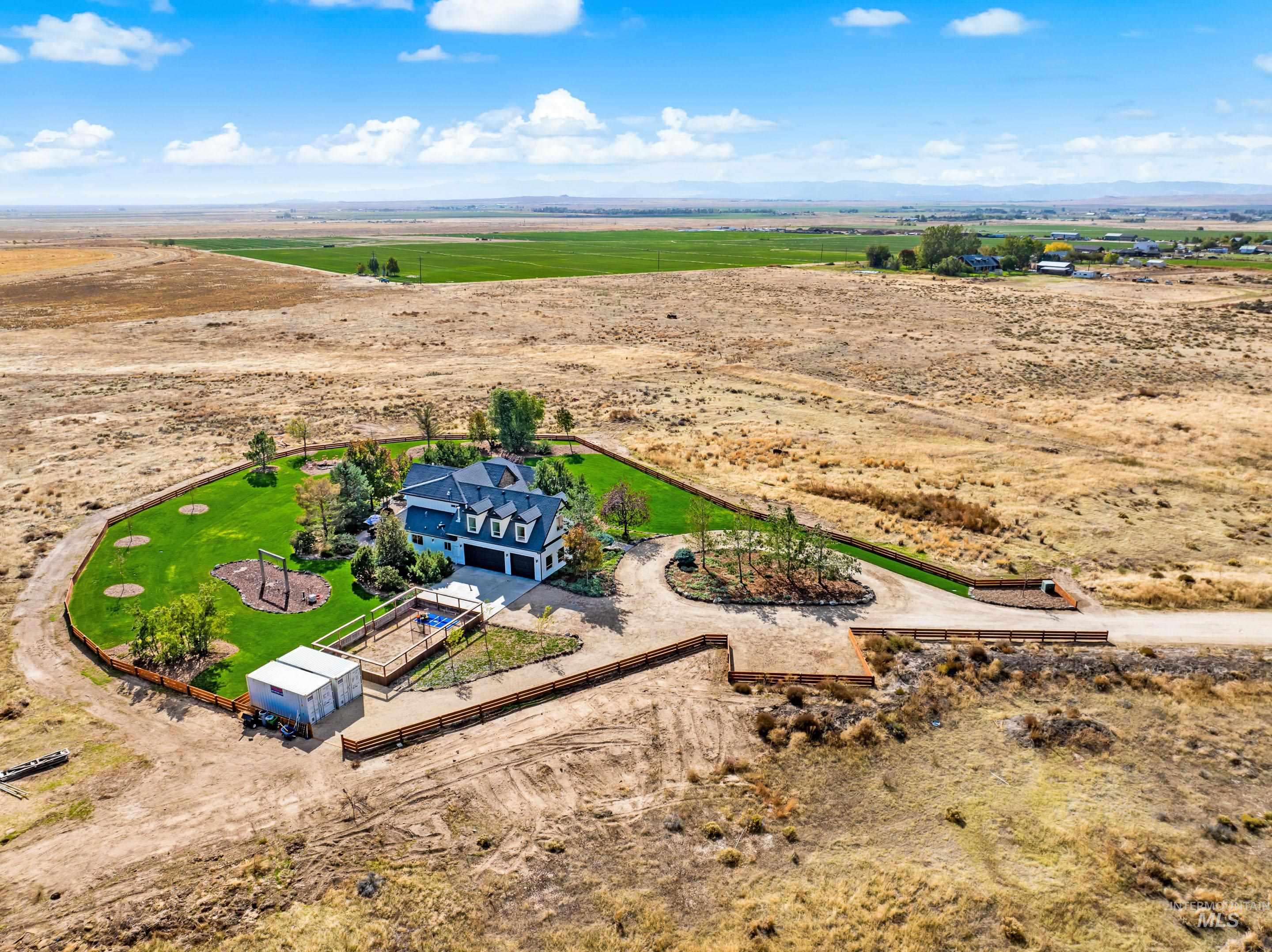 Expansive property featuring a large residence with a three-car garage, surrounded by a substantial manicured lawn