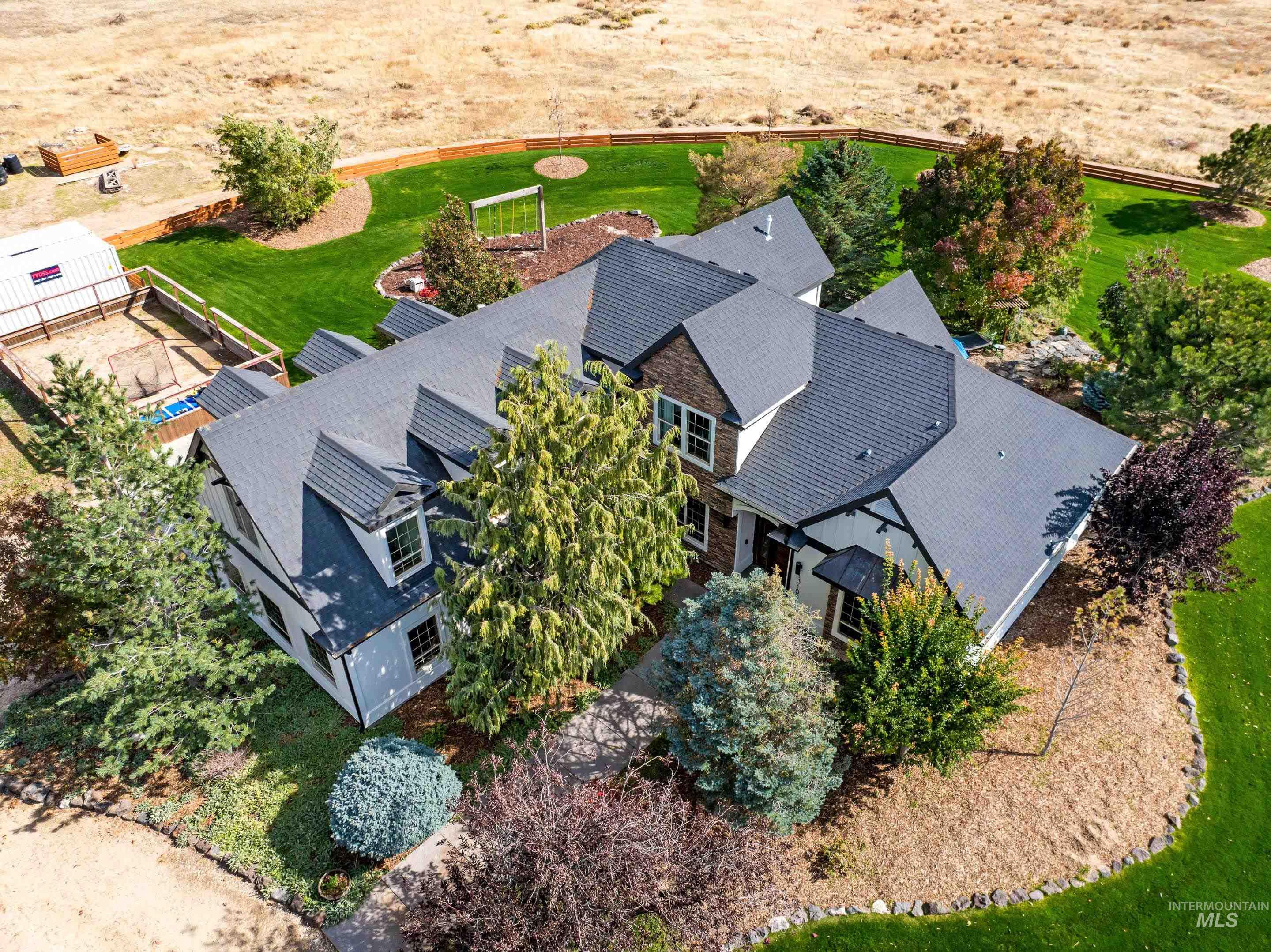 Spacious property featuring a large residence with a dark shingle roof, dormer windows, and a combination of light and dark siding