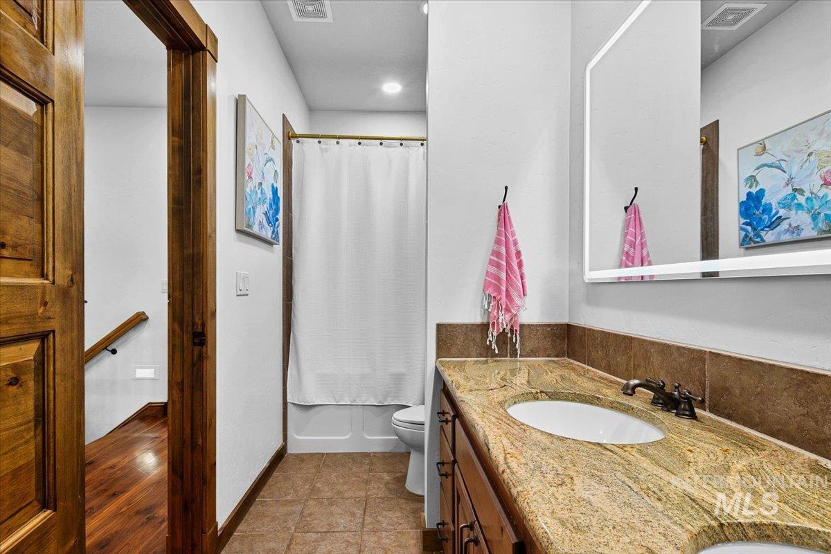 Full bathroom with a double vanity featuring a speckled countertop and integrated sinks