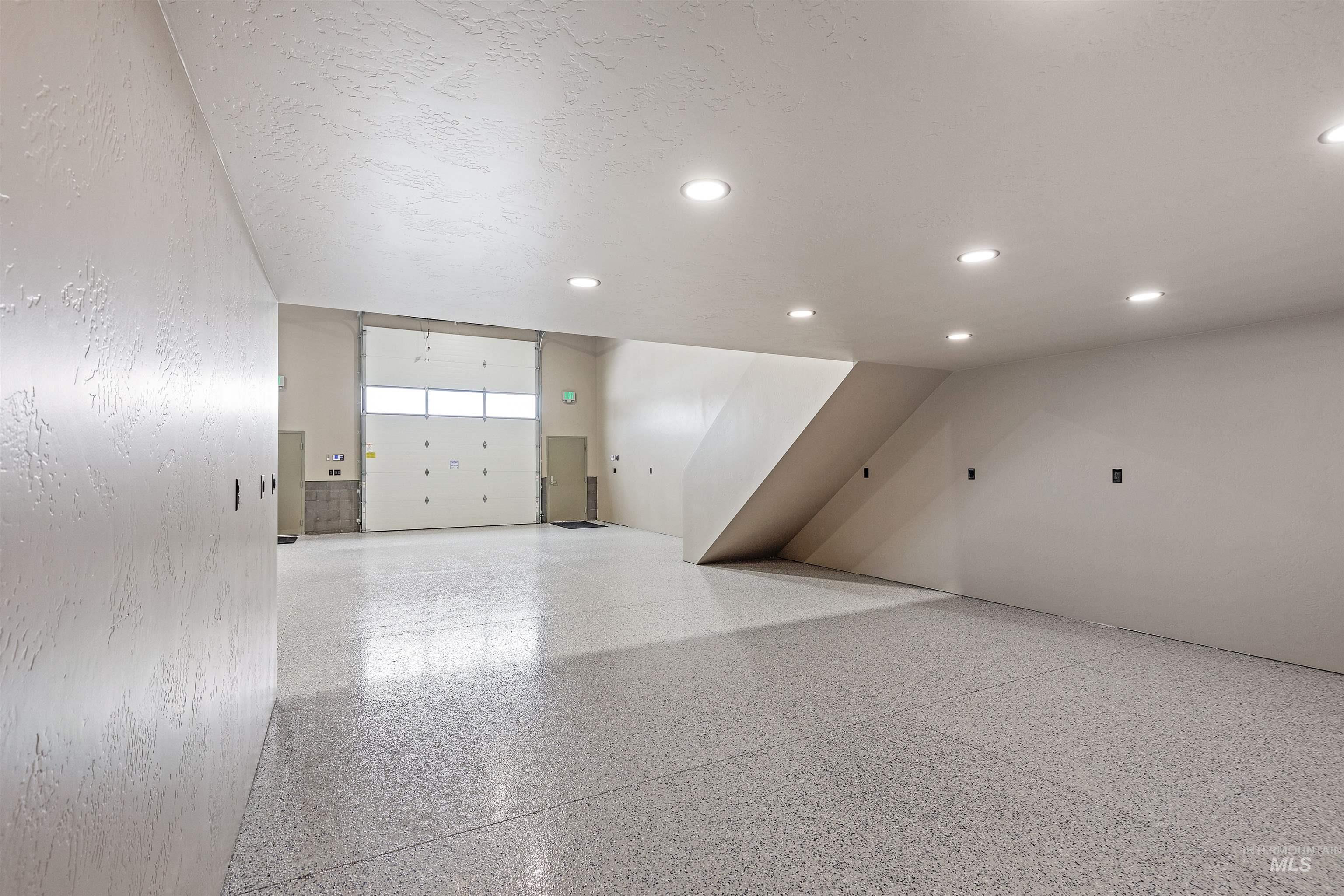 Empty room with dark speckled floor and recessed lighting