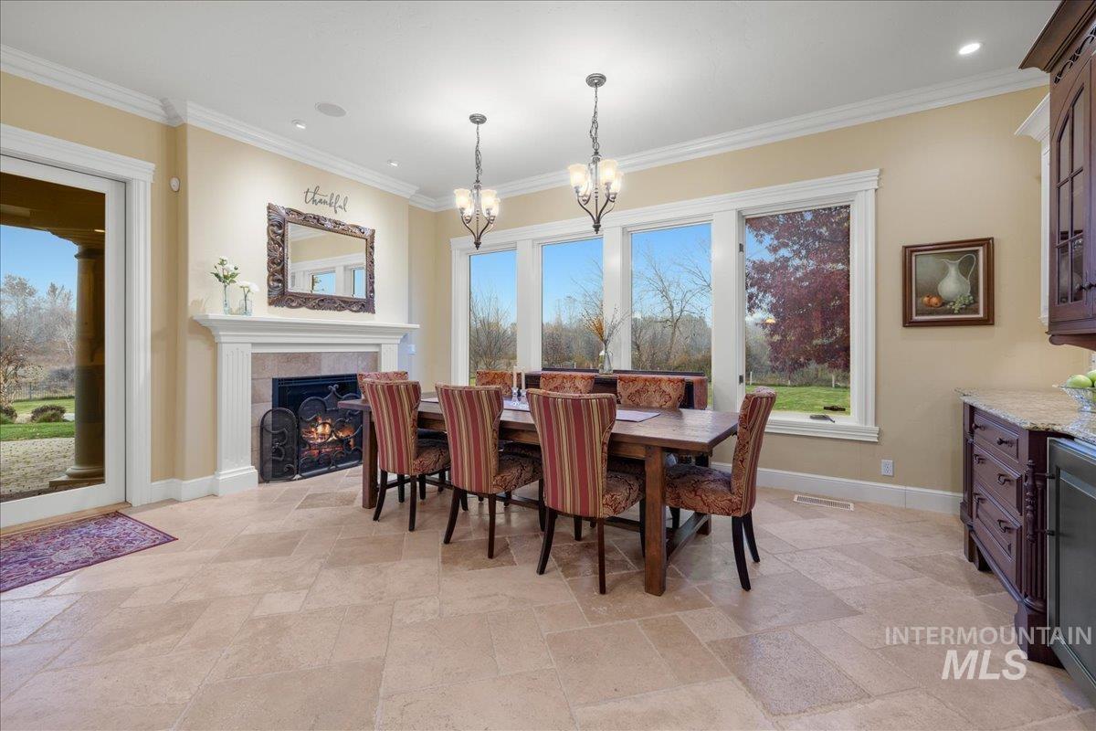 Dining room with a fireplace, stone tile floors, crown molding, and recessed lighting
