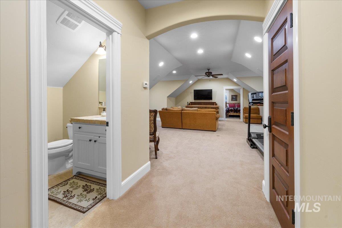 Corridor with vaulted ceiling, light carpet, and recessed lighting