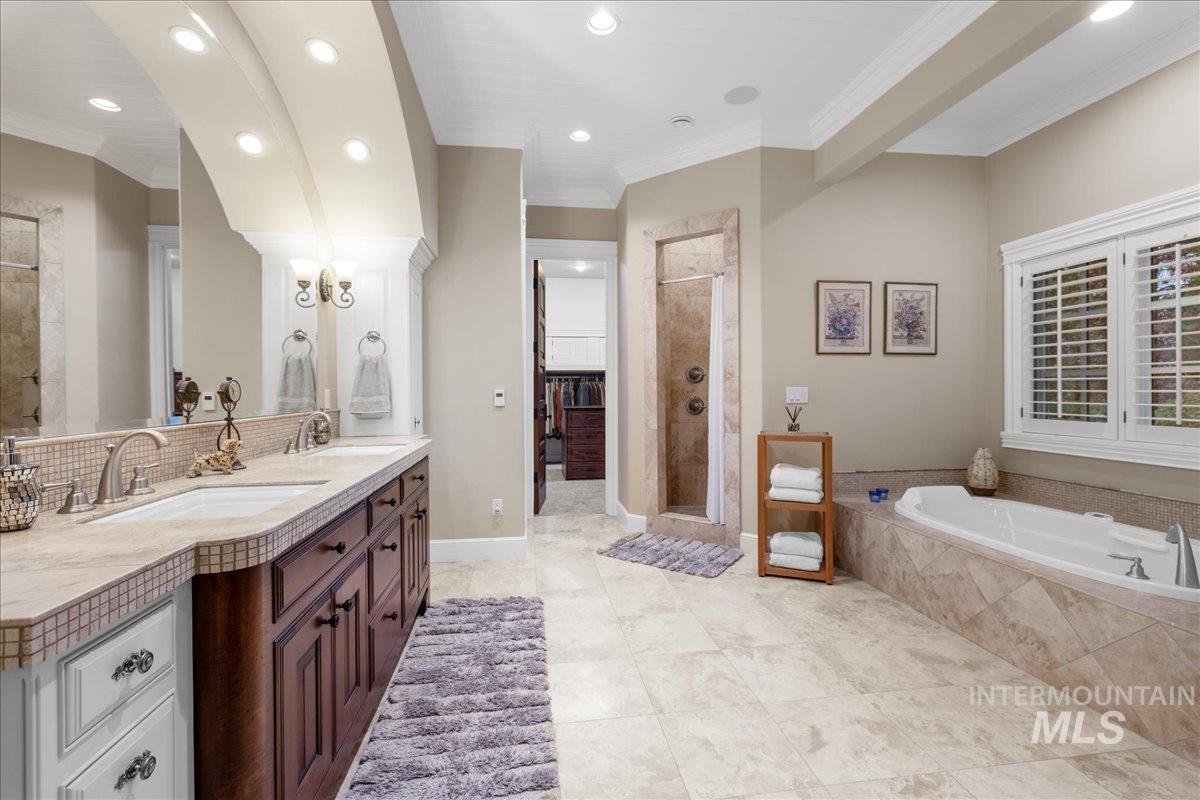 Bathroom with double vanity, a shower stall, a garden tub, crown molding, and recessed lighting