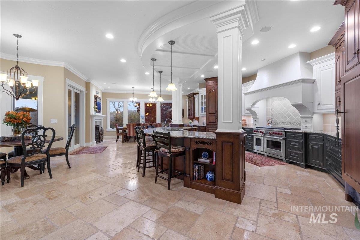 Kitchen with a kitchen bar, dark stone counters, a chandelier, backsplash, and a center island with sink