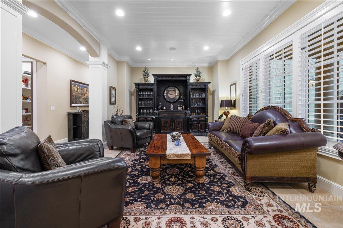 Living room with ornamental molding, decorative columns, recessed lighting, and arched walkways