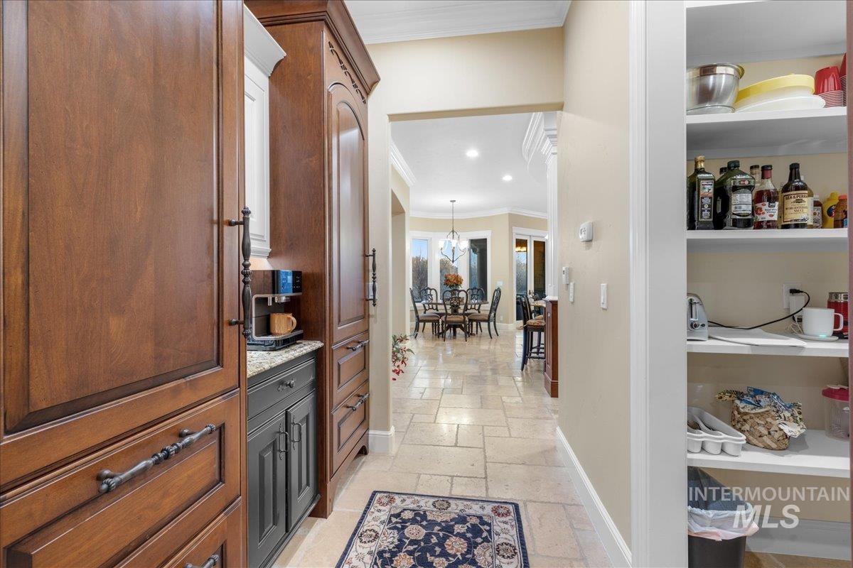 Hallway with stone tile floors, ornamental molding, and recessed lighting