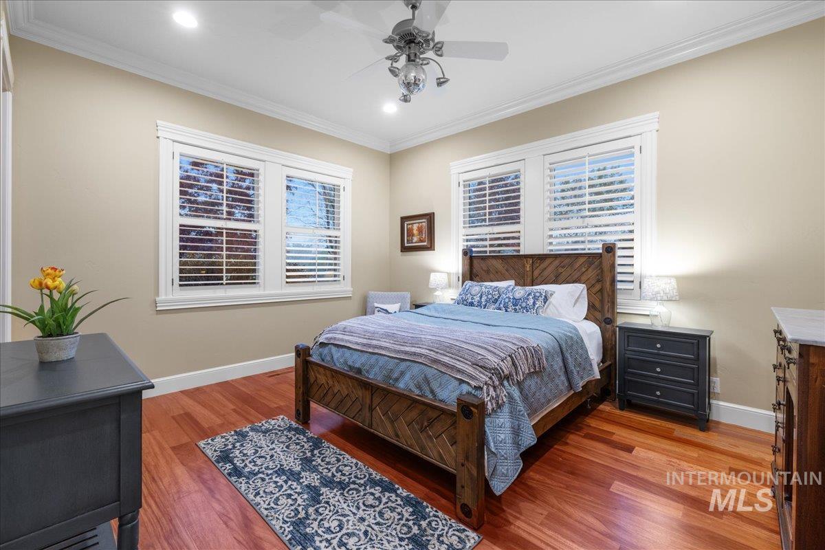 Bedroom featuring light wood-style floors, ornamental molding, a ceiling fan, recessed lighting, and multiple windows