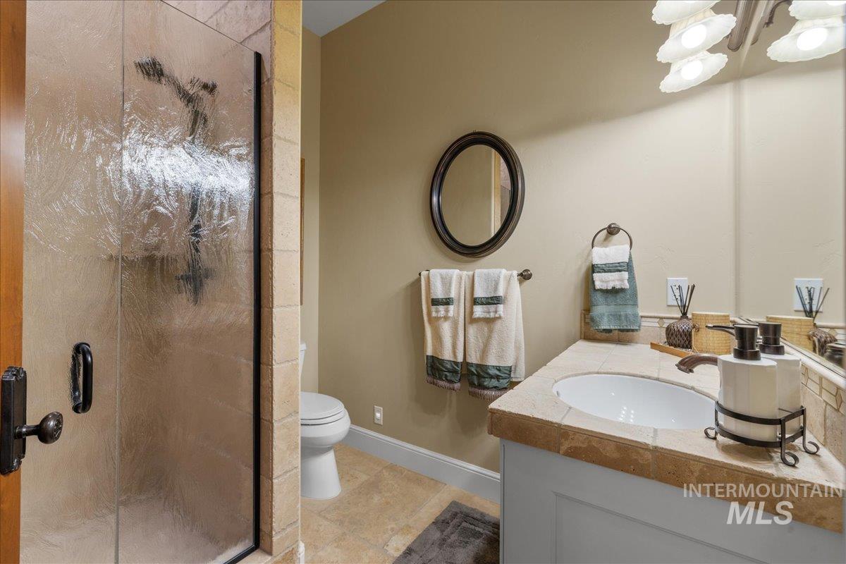 Bathroom featuring vanity, a shower stall, light tile patterned flooring, and a chandelier