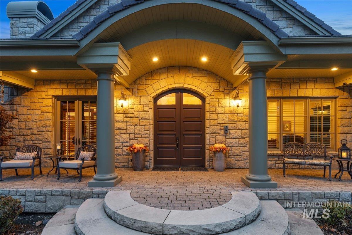 Entrance to property featuring french doors, covered porch, and stone siding