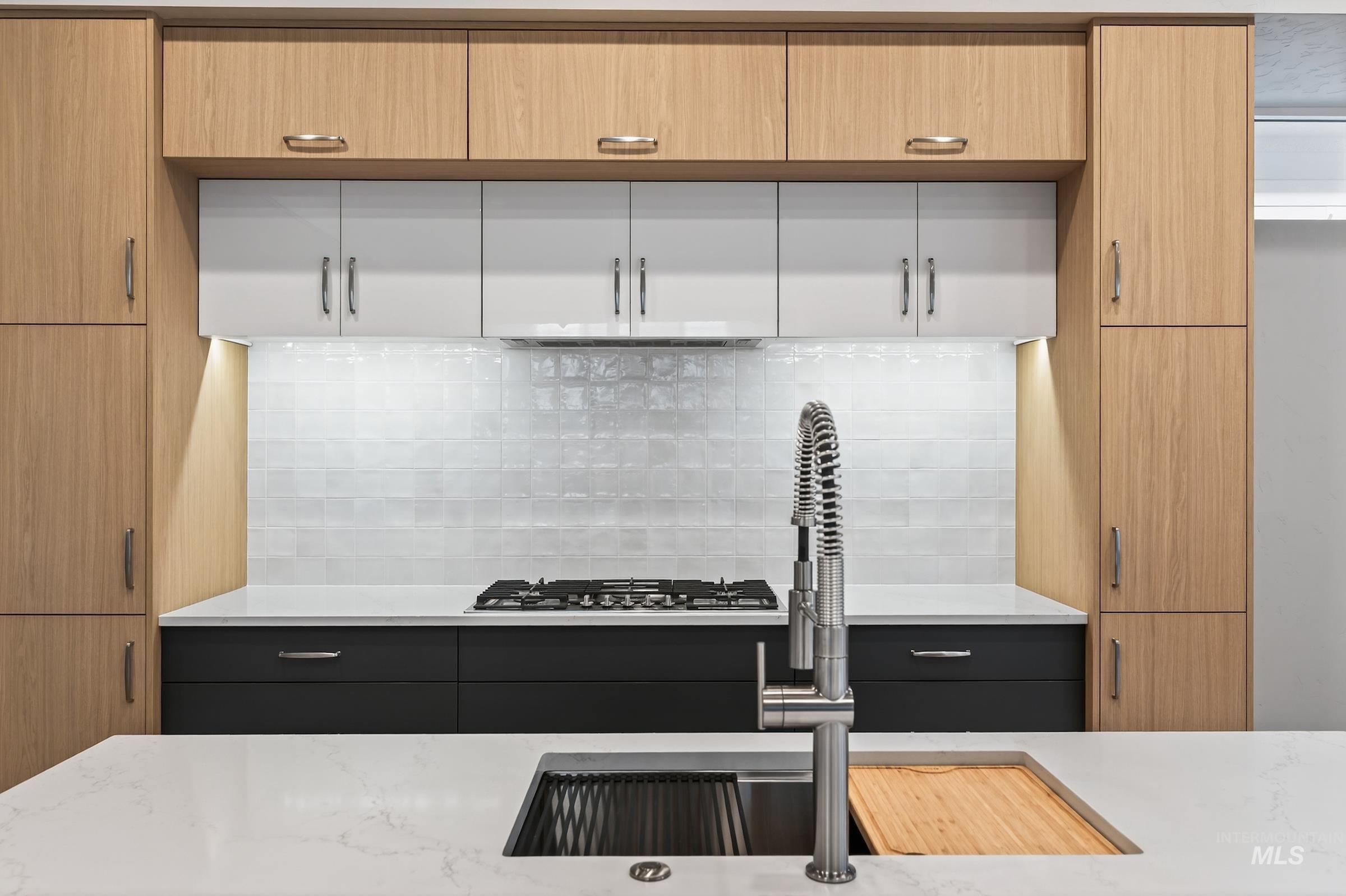Kitchen featuring light stone countertops, backsplash, and light brown cabinets