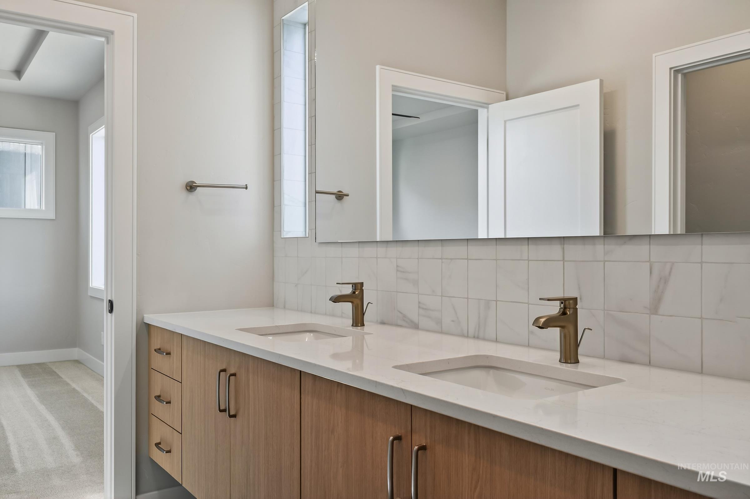 Bathroom featuring double vanity, decorative backsplash, and light carpet