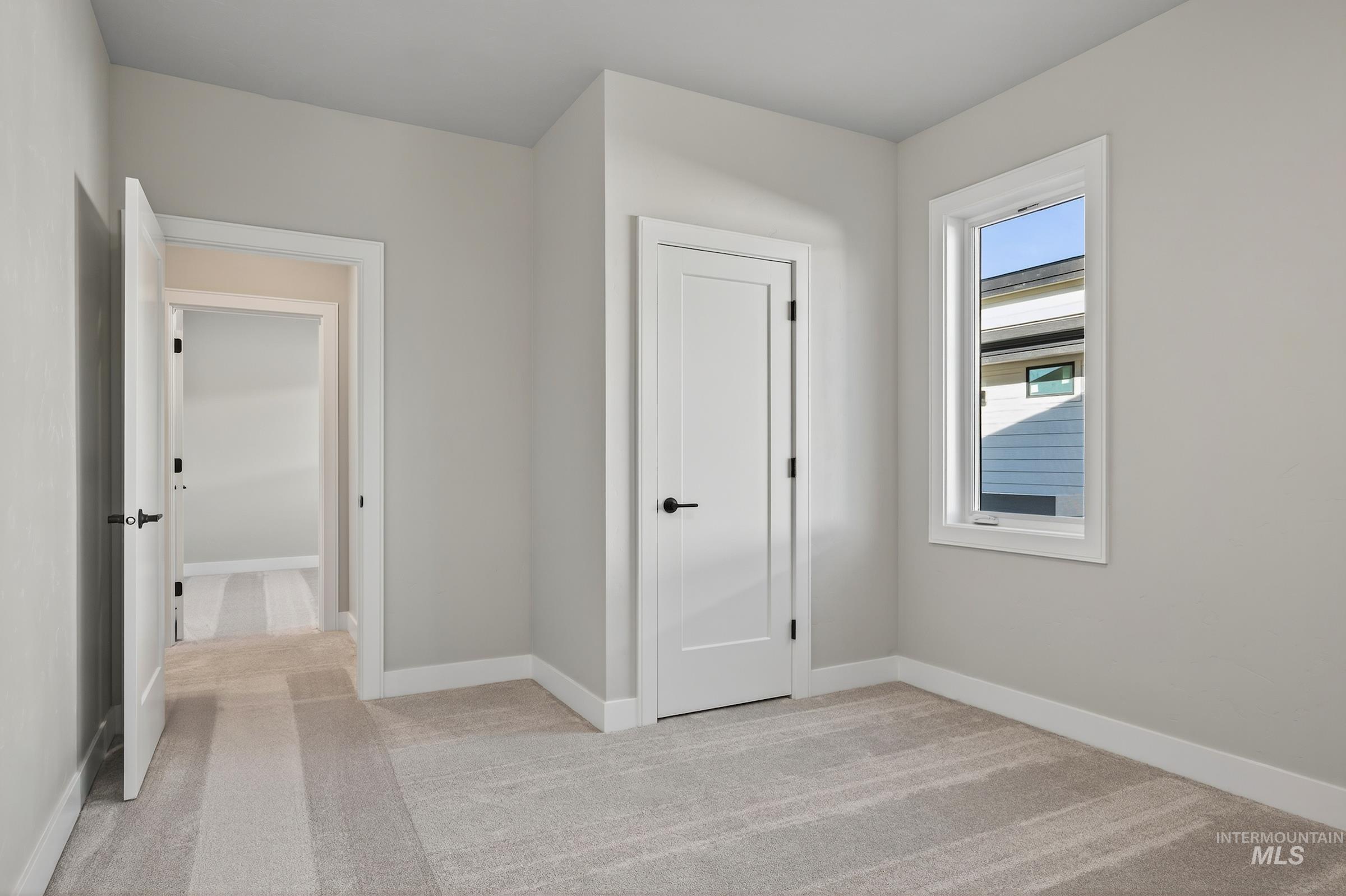 Unfurnished bedroom featuring light colored carpet and baseboards