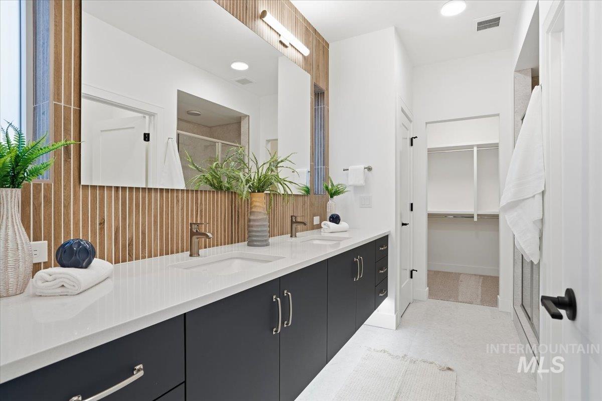 Full bathroom featuring a shower stall, double vanity, a spacious closet, and recessed lighting