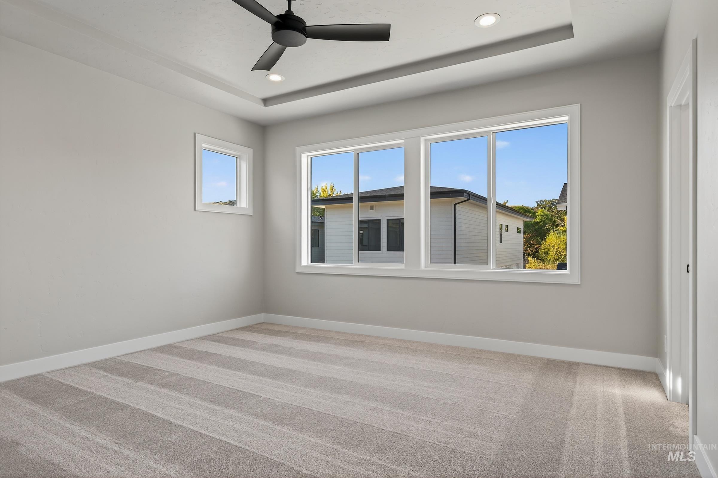 Unfurnished room with light carpet, a tray ceiling, ceiling fan, and recessed lighting
