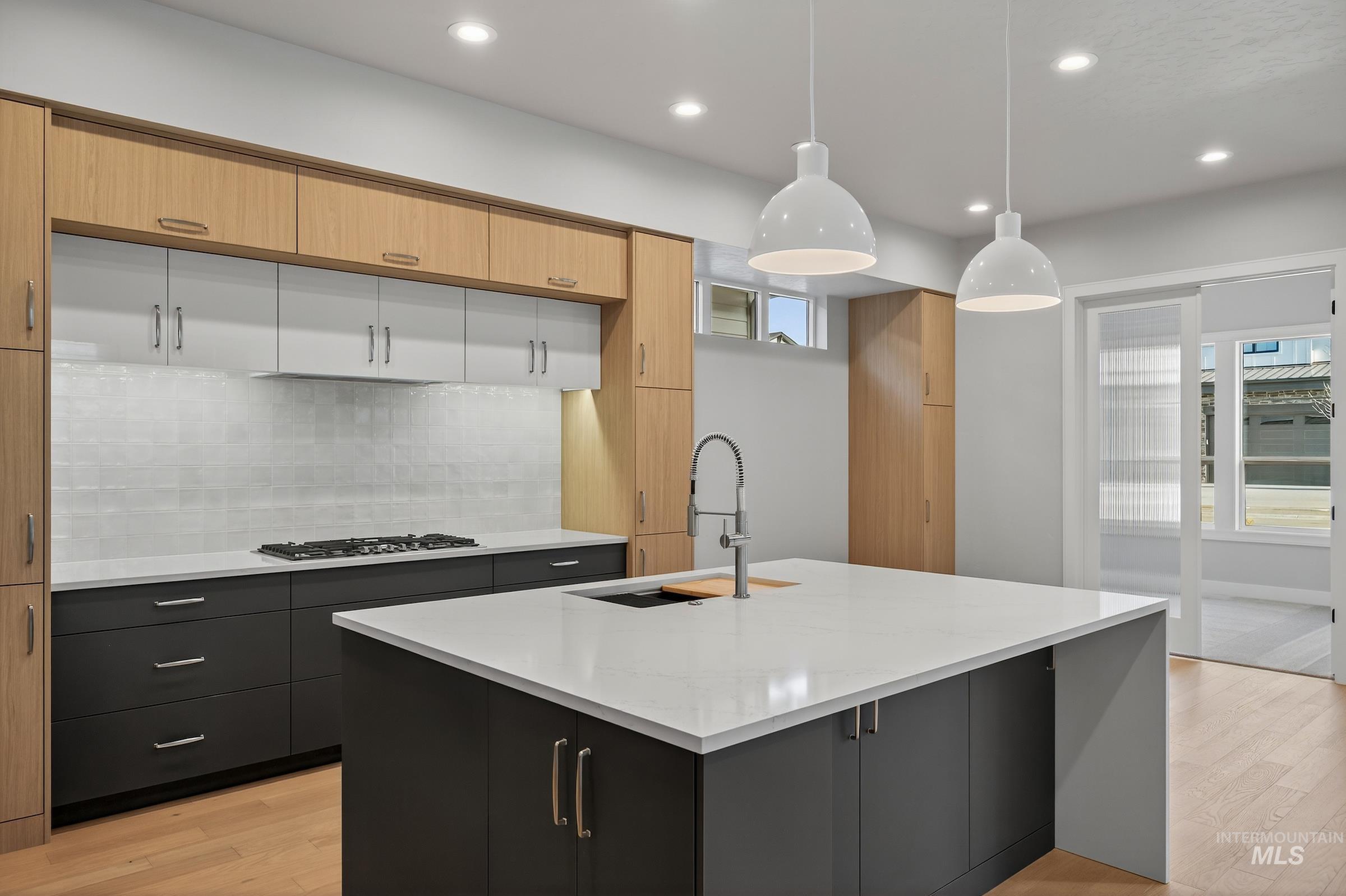 Kitchen featuring hanging light fixtures, healthy amount of natural light, white cabinets, light wood-type flooring, and recessed lighting