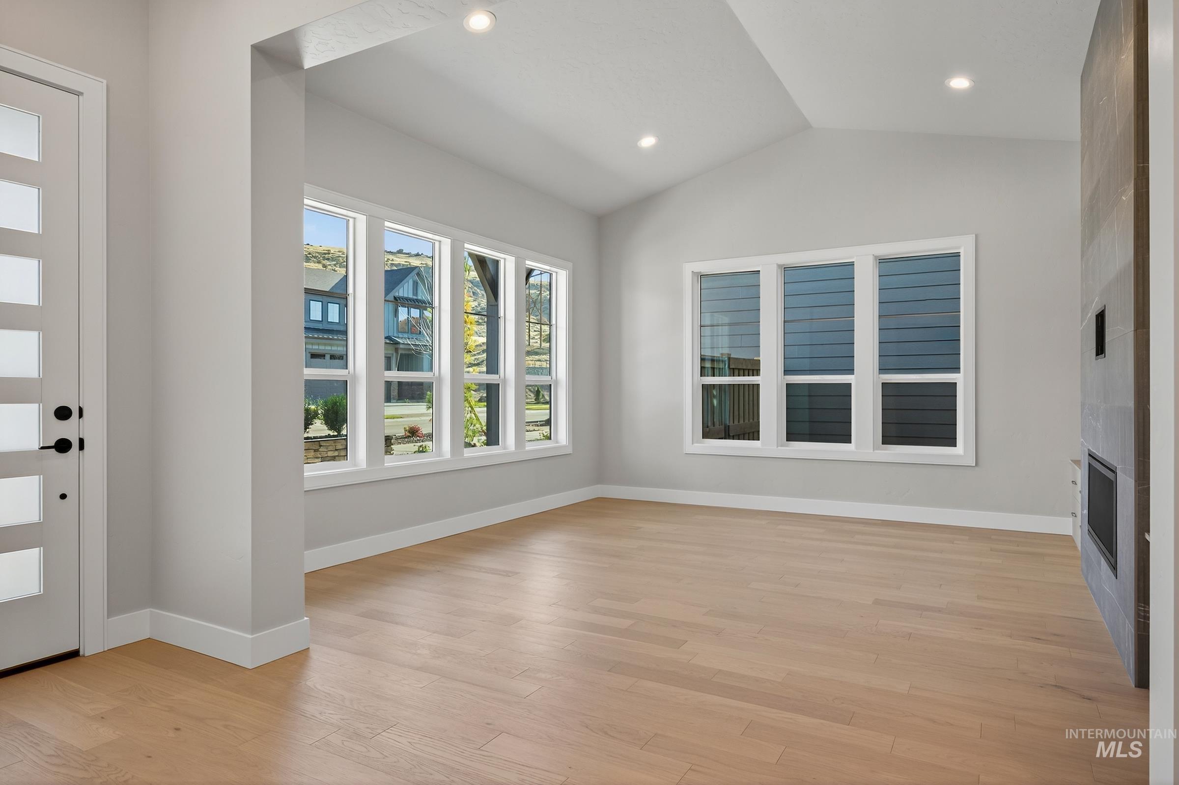 Foyer entrance with vaulted ceiling, light wood-style flooring, a fireplace, and recessed lighting