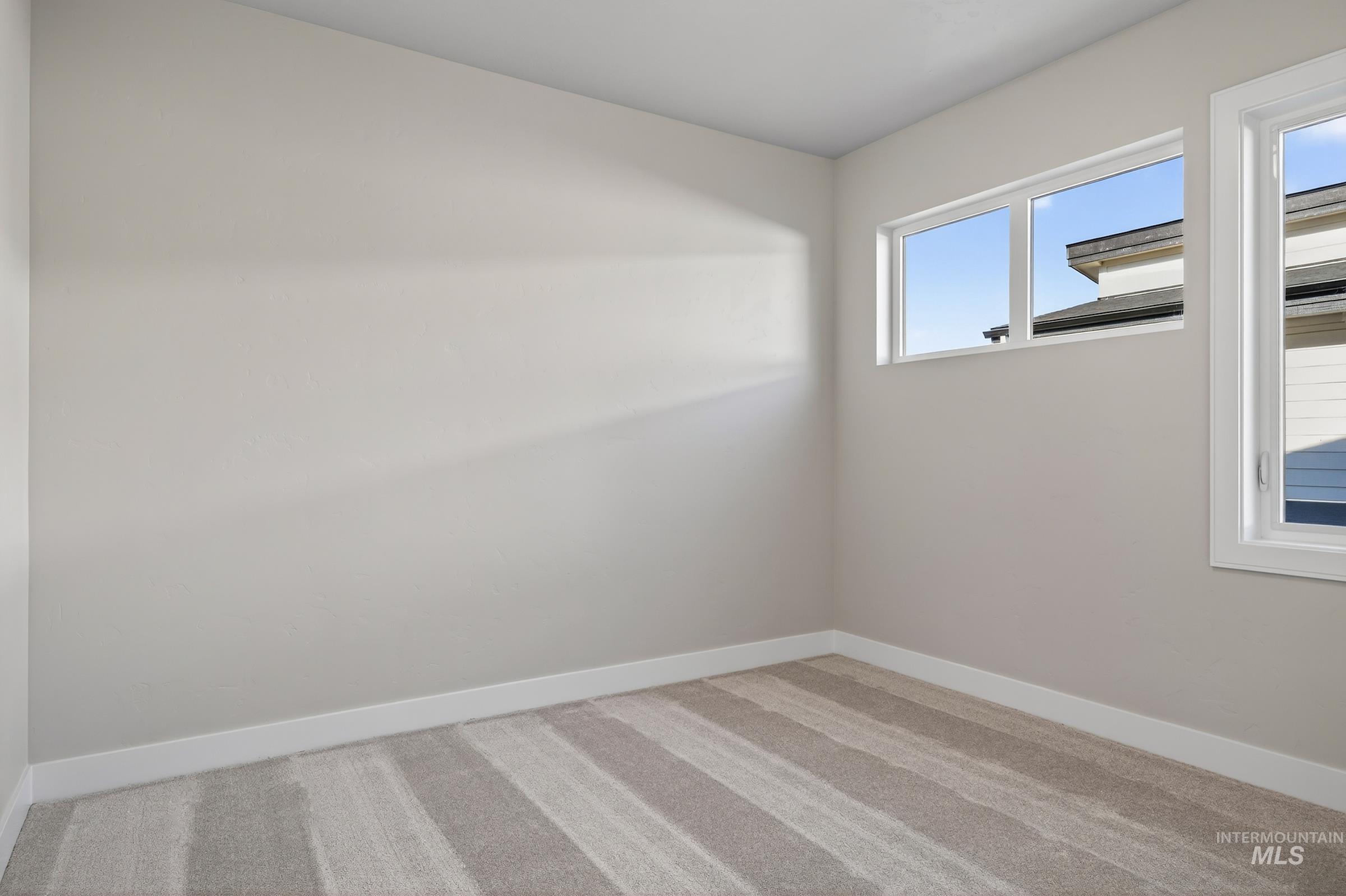 Spare room with light carpet and baseboards